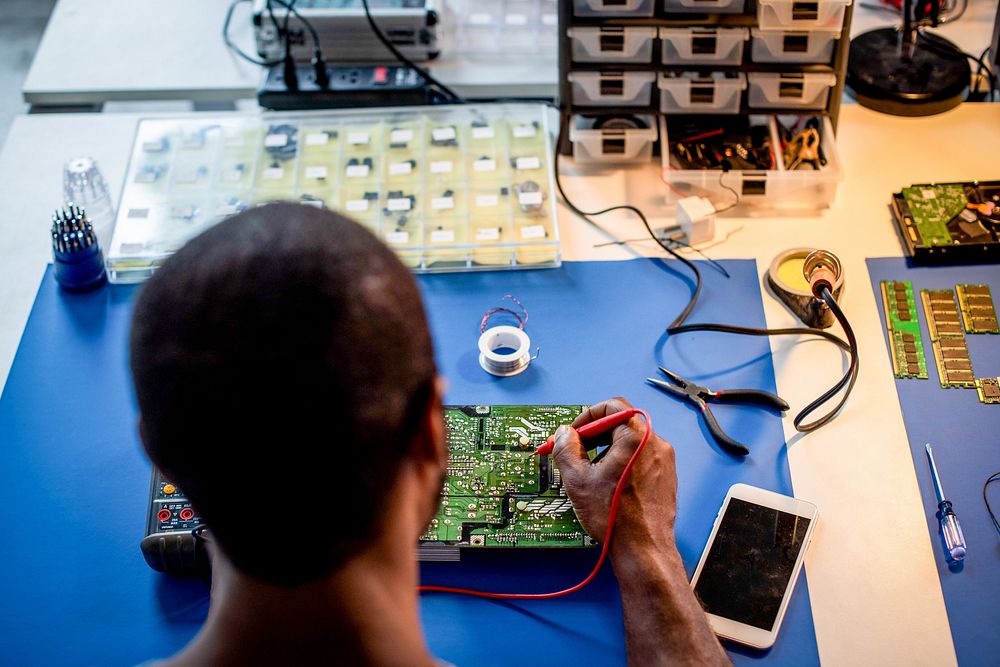 فني يعمل على دائرة إلكترونية دقيقة داخل ورشة صيانة، مناسب لموضوع التيست بوينت وصيانة اللوحات