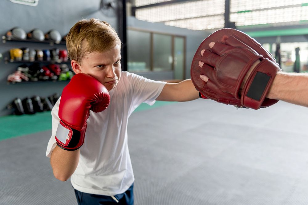 متدرب ملاكمة يركز أثناء الحصة داخل صالة رياضية، مناسب لموضوع تعلم الملاكمة من الأساس